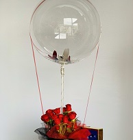 Clear Bubble balloon tied to a basket of 12 red roses
